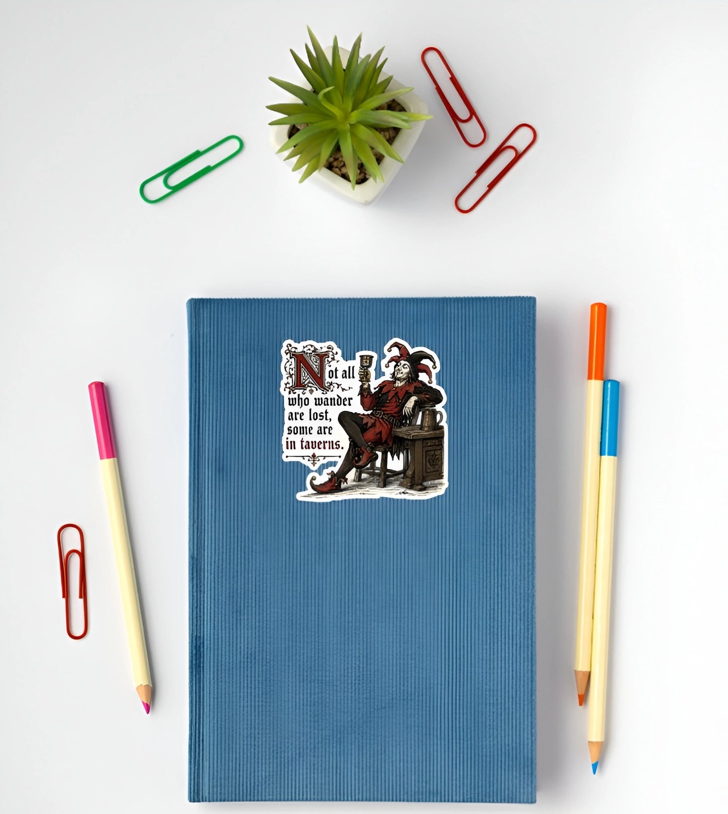 Not all who wander are lost tavern jester sticker displayed on a blue notebook