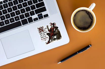 Medieval tavern jester sticker decorating a silver laptop beside a cup of coffee