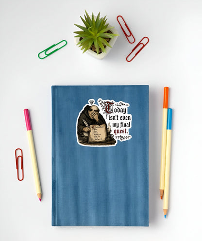 A blue hardcover notebook with a humorous sticker of a monk reading and the text 'I don't know, isn't even my final quest. 