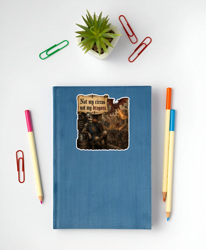 Medieval dragon meme sticker reading Not My Circus Not My Dragons on a blue notebook