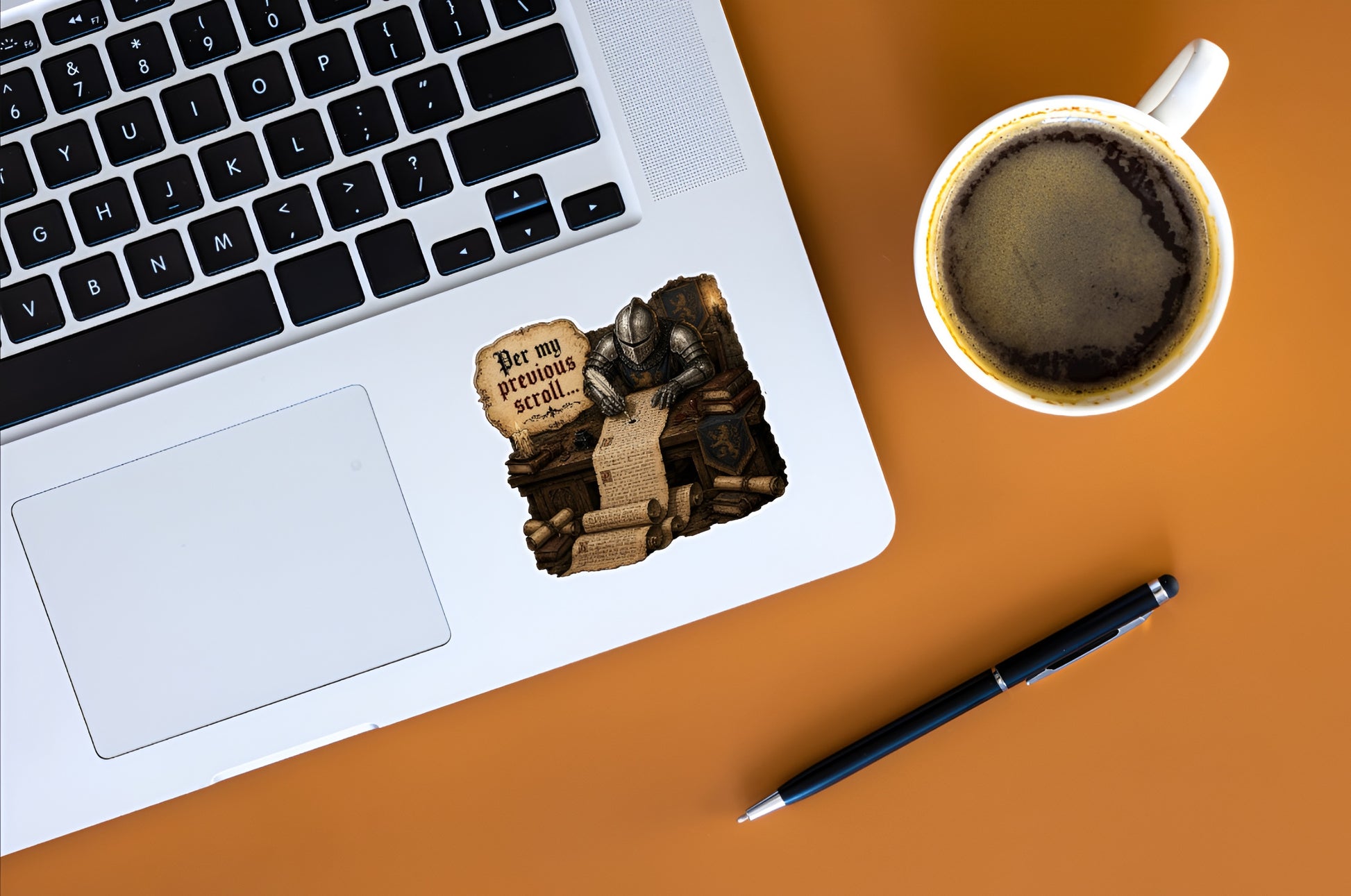 Per My Previous Scroll medieval knight office sticker displayed on a silver laptop beside coffee