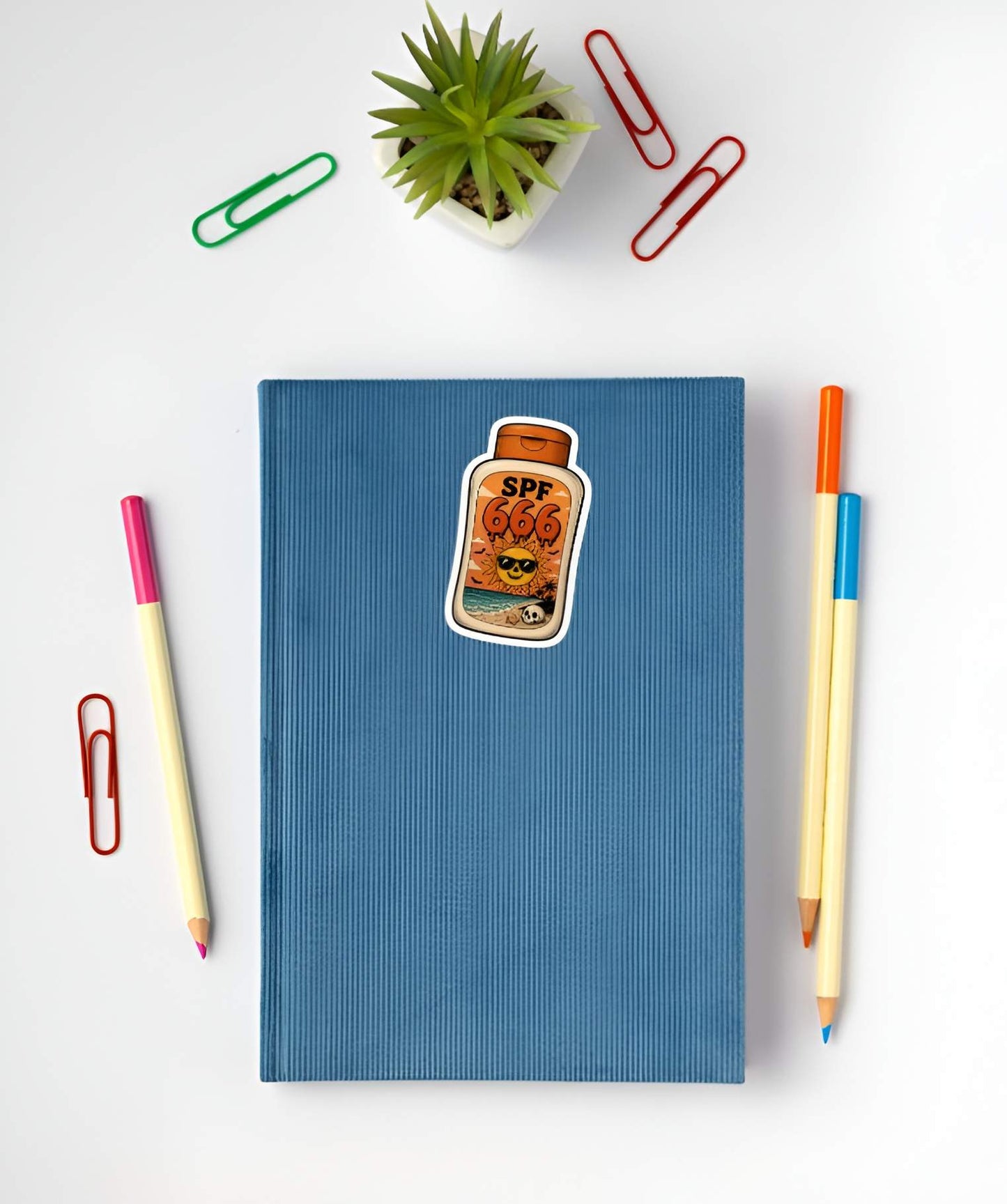 Blue notebook with a SPF 666 sticker on a white background with stationery items.