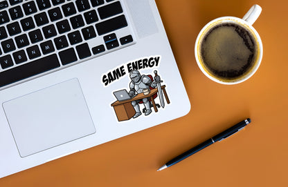 Funny Same Energy knight sticker displayed on a silver laptop next to coffee