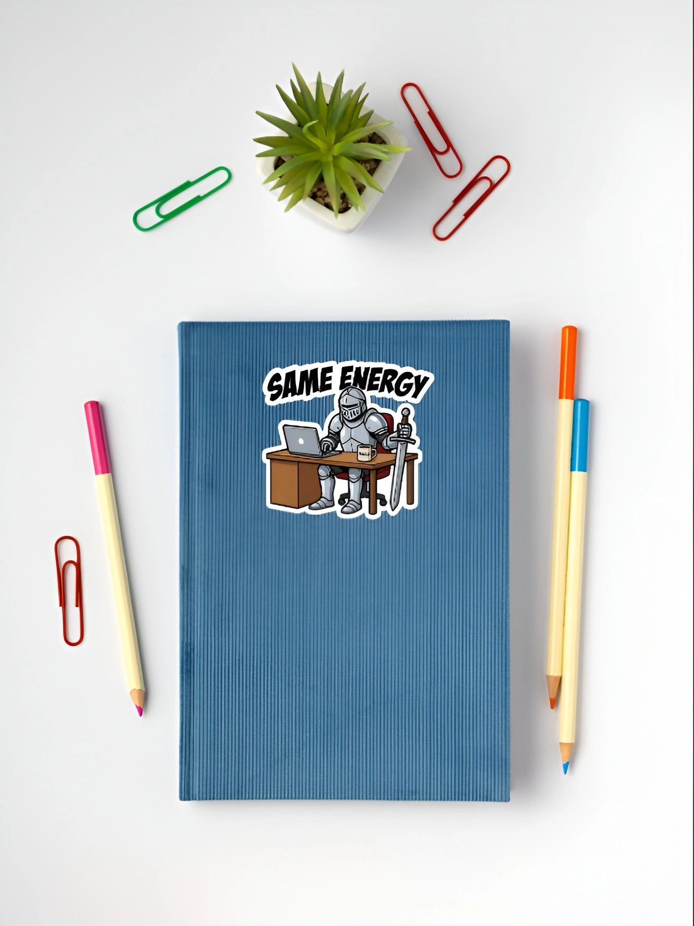 Same Energy knight meme sticker placed on a blue notebook