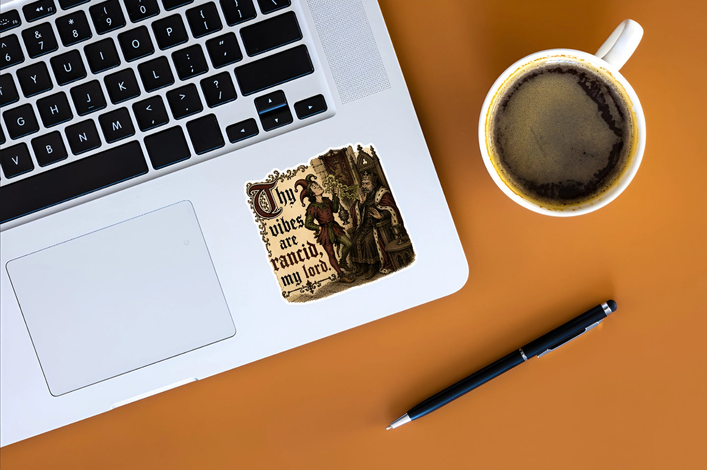 Thy Vibes Are Rancid medieval meme sticker displayed on a silver laptop beside coffee