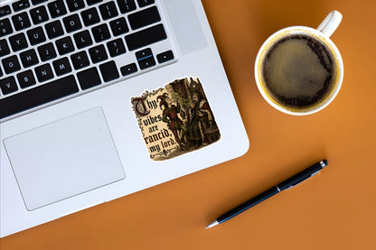 Thy Vibes Are Rancid medieval meme sticker displayed on a silver laptop beside coffee