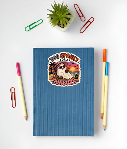 Blue notebook with a sunburn-themed sticker on a white background with stationery items.