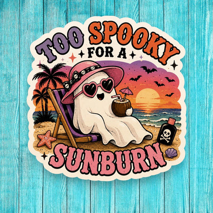 Sticker with a ghost on a beach chair, palm trees, and sunset text 'Too Spooky for a Sunburn' on a blue wooden background.