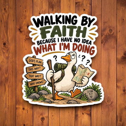 A die-cut cartoon sticker displayed on a brown wood plank background. The sticker features a white goose holding a hiking stick and map, with the text 'WALKING BY FAITH BECAUSE I HAVE NO IDEA WHAT I'M DOING' above it.