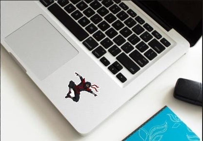 Laptop with a sticker on the lid, placed on a white surface with a phone and blue card beside it.