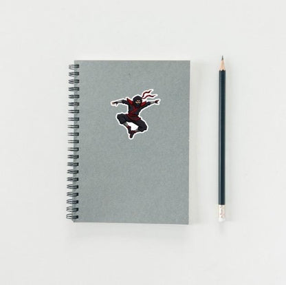 Notebook with a superhero sticker and a pencil on a light gray background