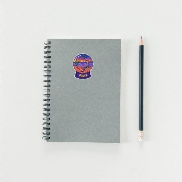 Gray spiral-bound notebook with a colorful sticker on a white background