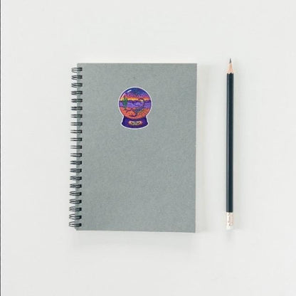 Gray spiral-bound notebook with a colorful sticker on a white background
