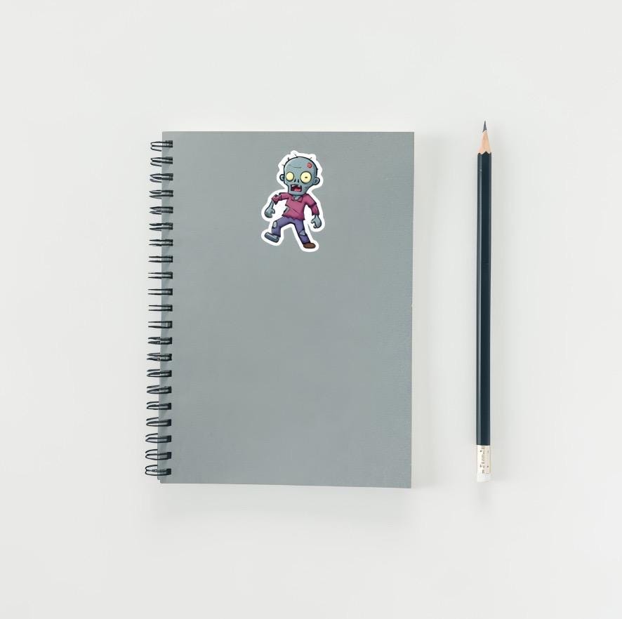 Gray notebook with a zombie sticker and a pencil on a white background