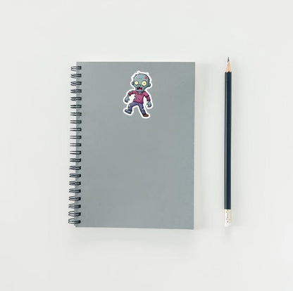 Gray notebook with a zombie sticker and a pencil on a white background