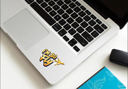Laptop with a sticker on the lid displaying 'I'm so fly' on a white surface.
