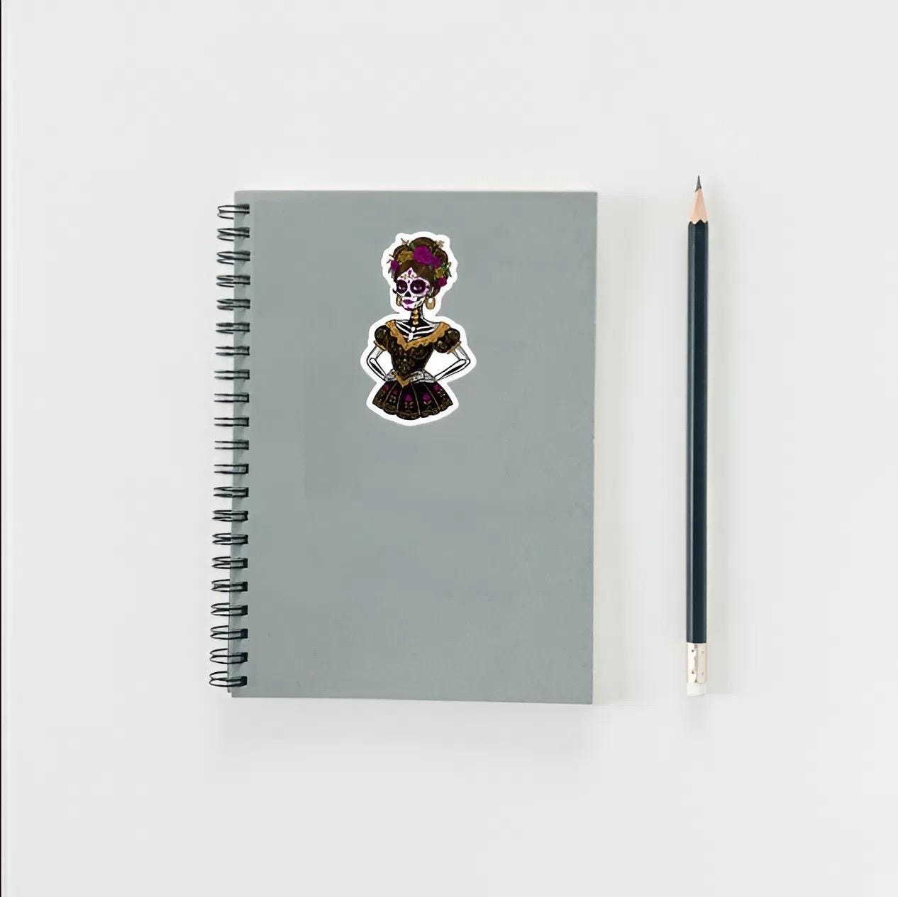 Gray notebook with a skeleton sticker and a pencil on a white background