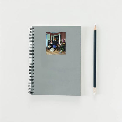 Gray spiral-bound notebook with a photo on the cover and a black pencil next to it on a light gray background