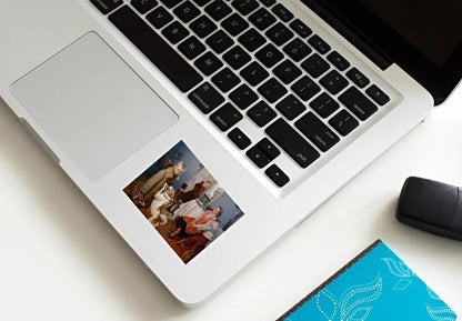 Laptop with a photo album attached to it on a white surface.