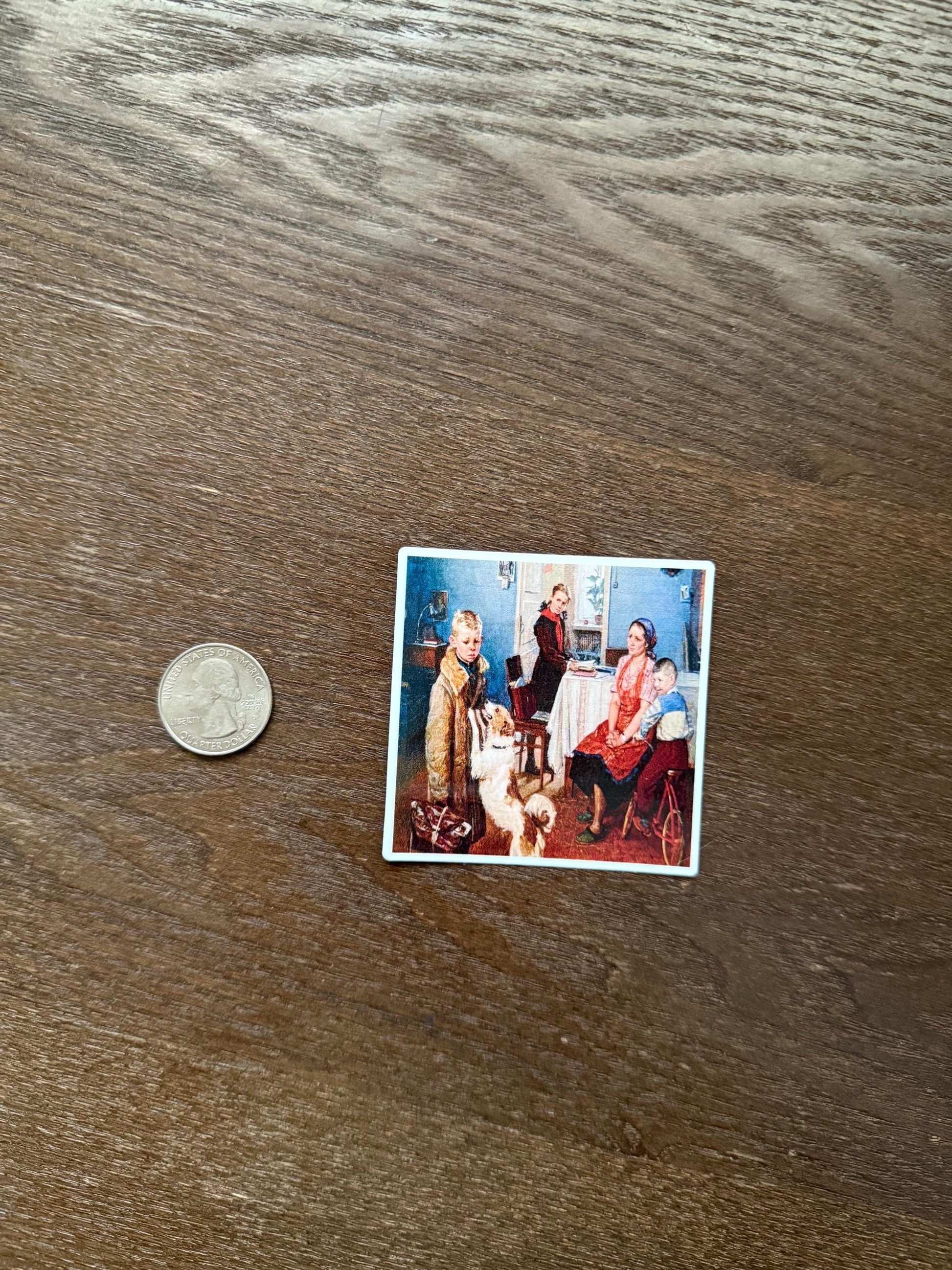 Small photograph of a family with a dog on a wooden surface next to a coin for scale.