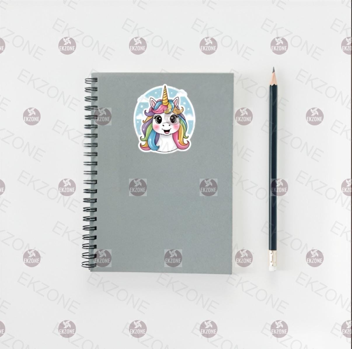 Gray notebook with a unicorn sticker and a pencil on a white background with brand logos.