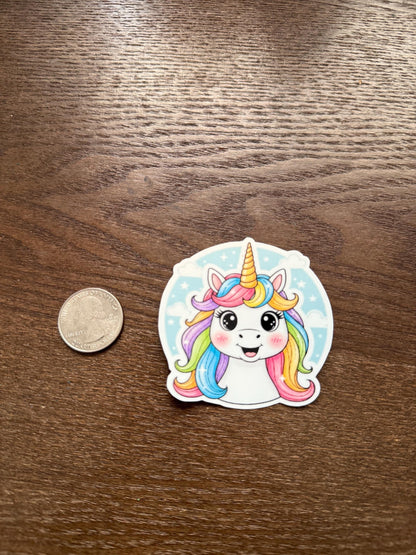 Sticker of a colorful unicorn with a coin for scale on a wooden surface