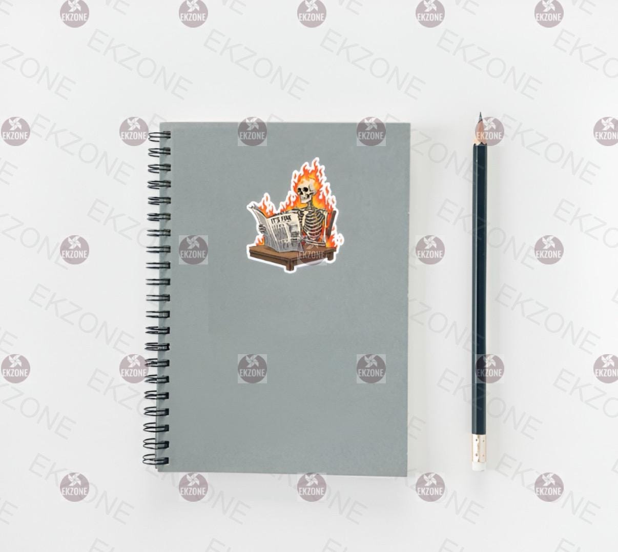 Gray notebook with a sticker of a skeleton in flames and a pencil on a white background