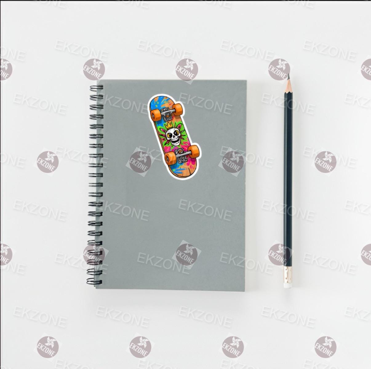 Gray notebook with a colorful skateboard sticker and a pencil on a white background.