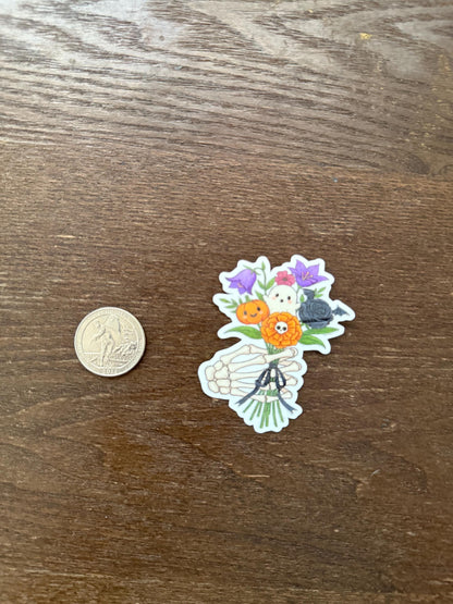 Sticker of a hand holding flowers next to a coin on a wooden surface