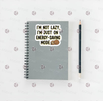 Notebook with a sticker saying 'I'm not lazy, I'm just on energy-saving mode' and a pencil on a white background