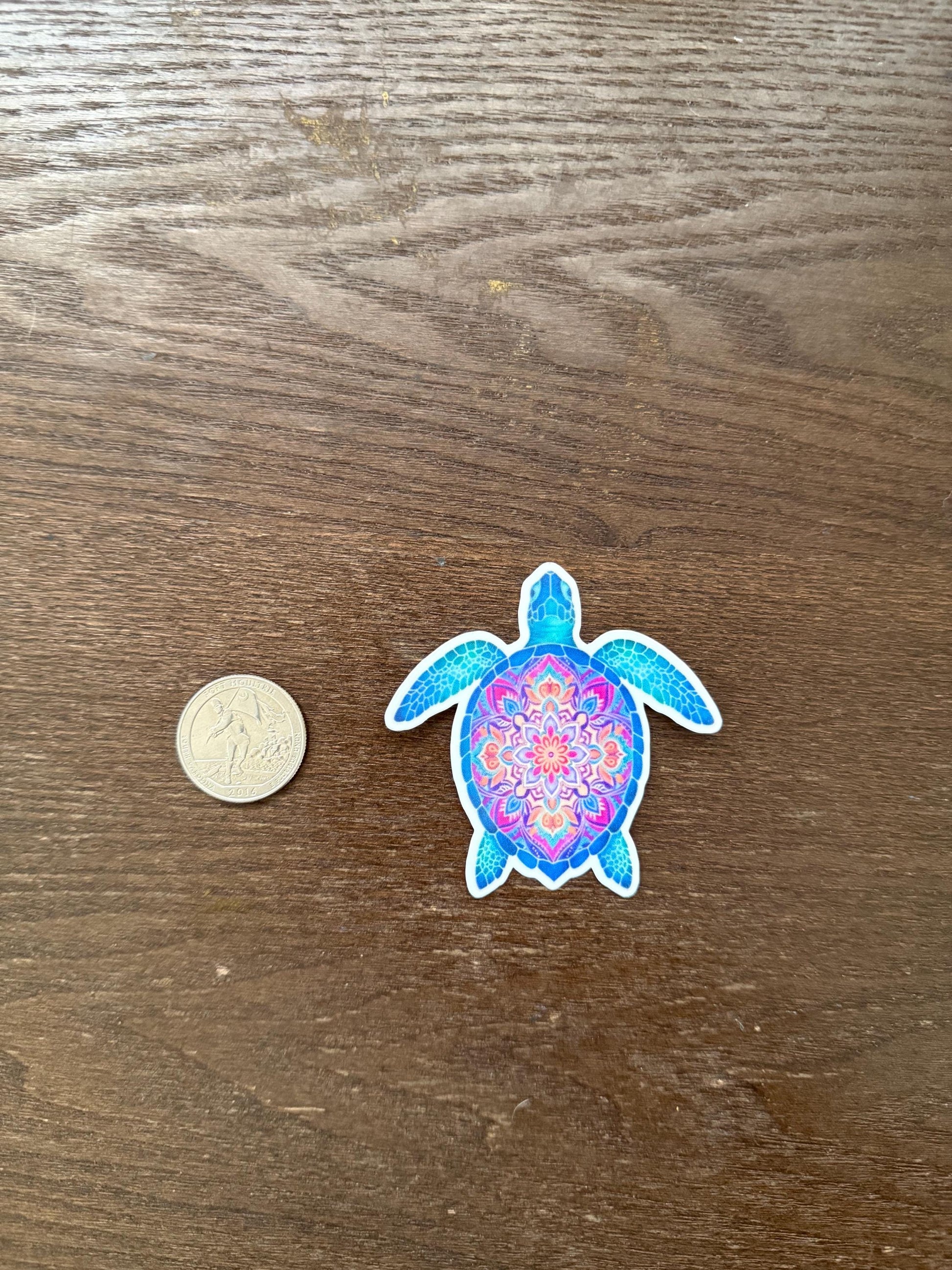 Colorful turtle sticker next to a coin on a wooden surface