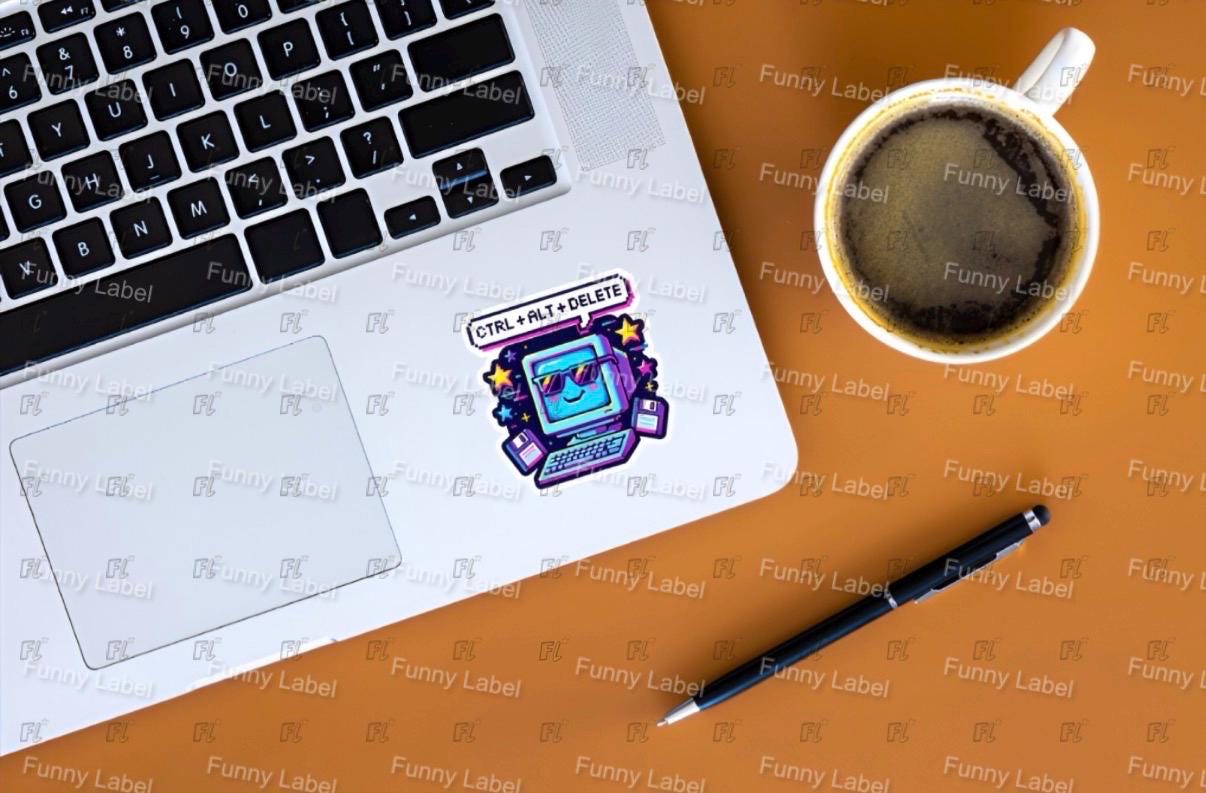 Laptop with a sticker on a desk next to a coffee cup and pen
