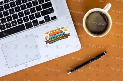 Laptop with a sticker on a brown surface with a coffee cup and pen.