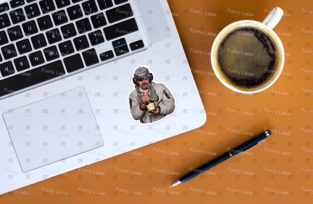 Laptop with a coffee cup, pen, and photo of a Nicholas Maduro on a brown surface with 'Funny Labels' branding.
