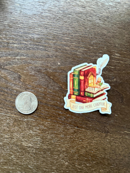Sticker with books and a banner on a wooden surface next to a coin for scale.