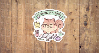 A flat, isolated vinyl sticker featuring an adorable cartoon illustration of a determined little chipmunk wearing tiny glasses, sitting at a miniature desk surrounded by acorns and a tiny notebook, under the bold text "Planning My Empire."