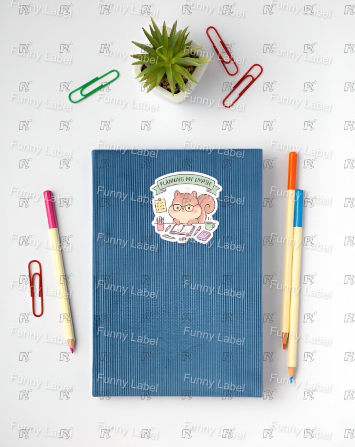 Blue notebook with a sticker on a white surface with stationery items