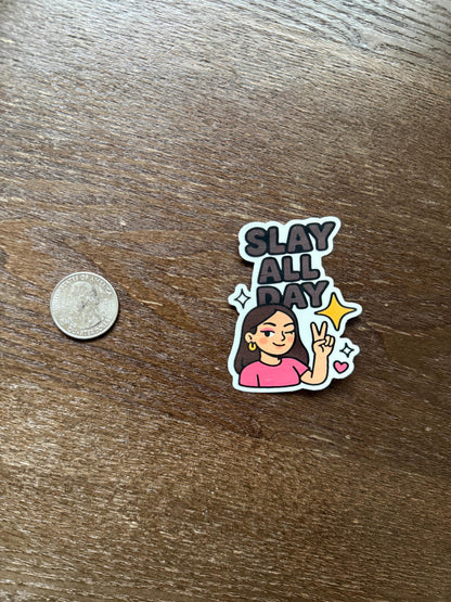 Sticker with 'Slay All Day' text and a person's illustration on a wooden surface with a coin for scale.