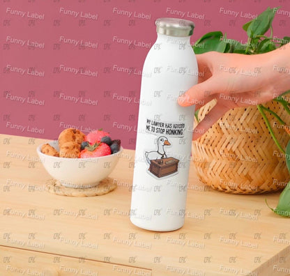 White water bottle with a humorous design on a wooden table with a pink background.