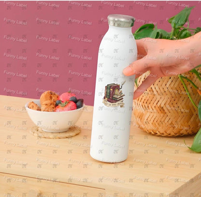 White bottle with a label held by a hand on a wooden surface with a pink background.