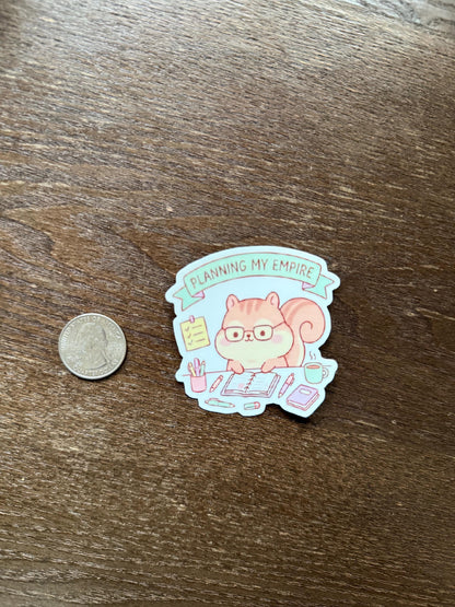 Sticker of a squirrel planning on a wooden surface with a coin for scale.