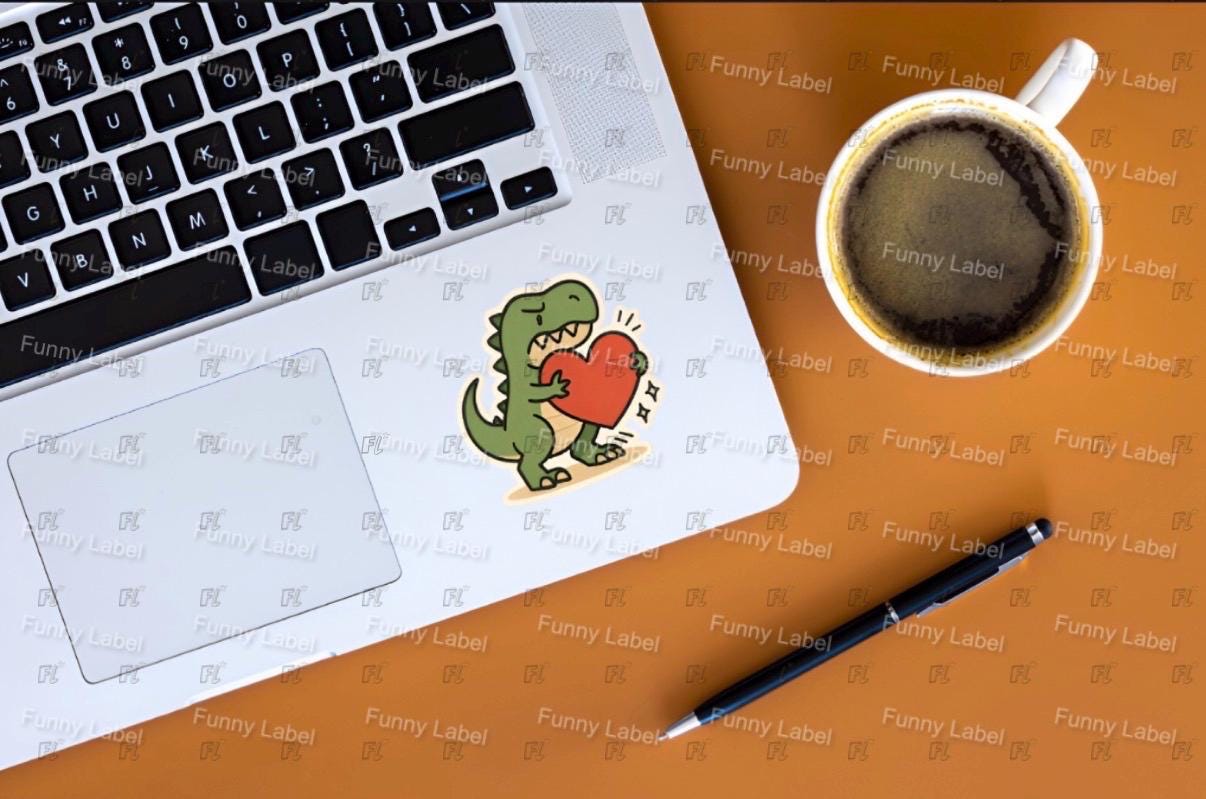 Laptop with a dinosaur sticker, coffee cup, and pen on an orange surface with 'Funny Label' branding.
