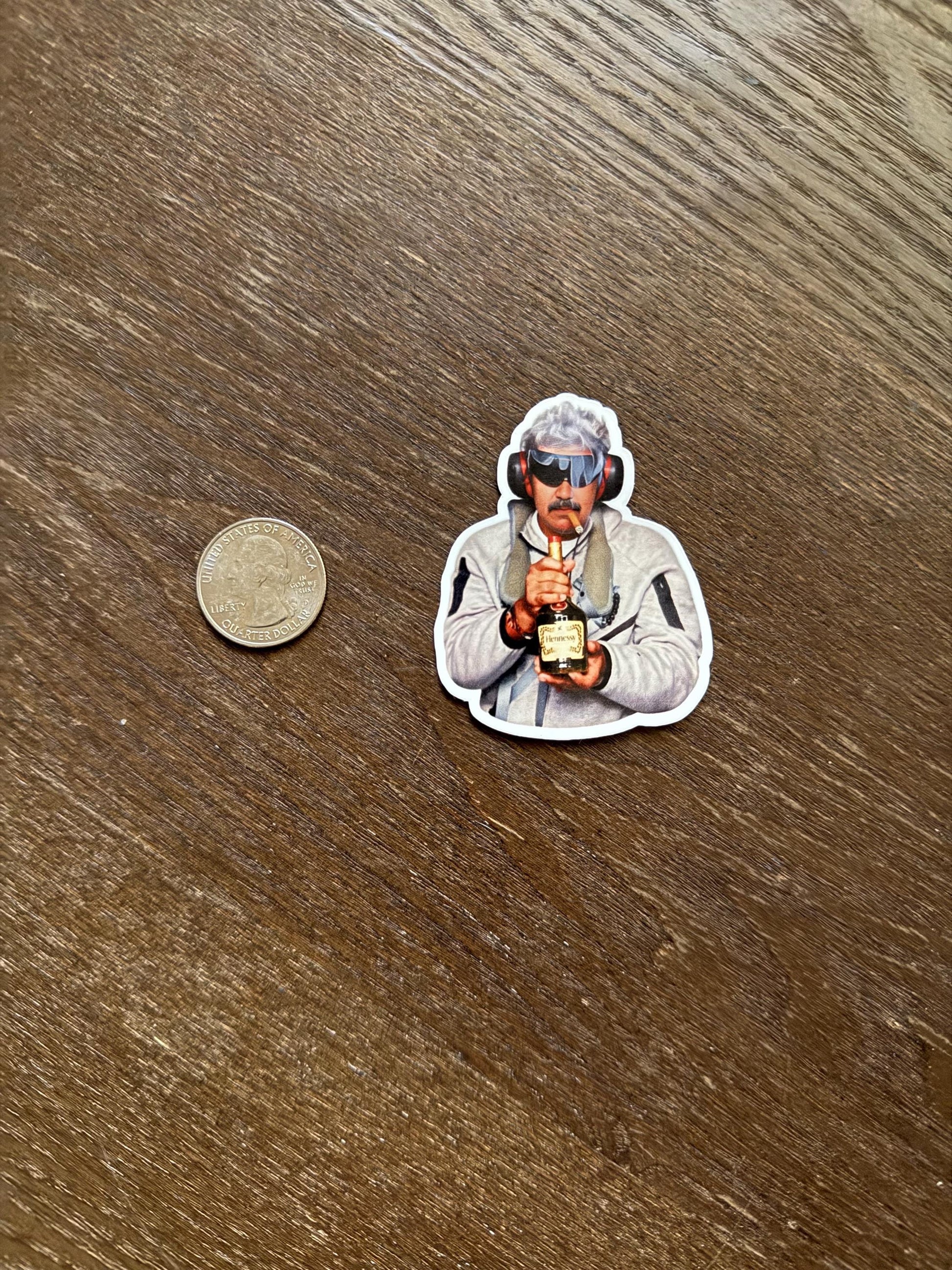 Sticker of a person holding a trophy next to a coin on a wooden surface